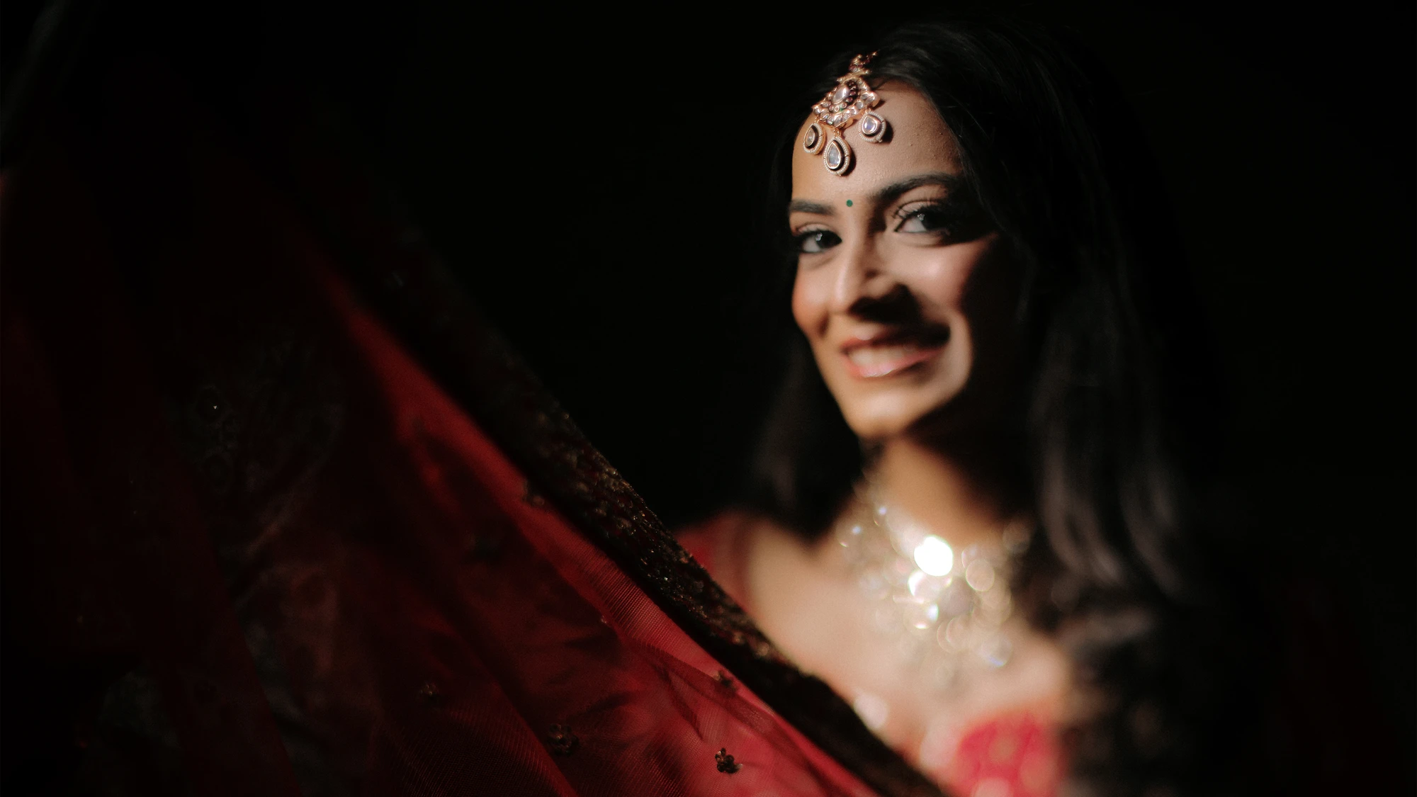 Radiant bride close-up with sheer red veil
